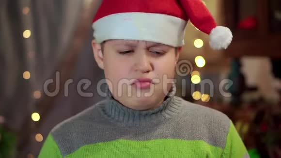穿着圣诞老人的毛衣和帽子的男孩心烦意乱他没有天赋特写镜头对抗视频的预览图