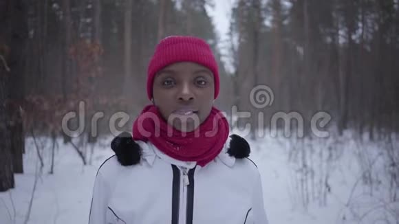 美国黑人女孩走在冬季森林看镜头然后向上穿暖和夹克的漂亮女孩视频的预览图