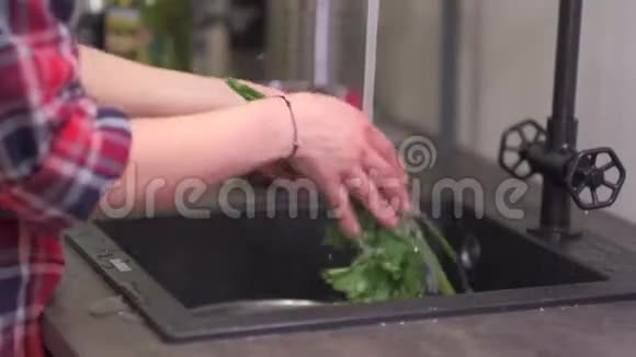 年轻的家庭主妇在厨房的水槽里洗蔬菜视频的预览图