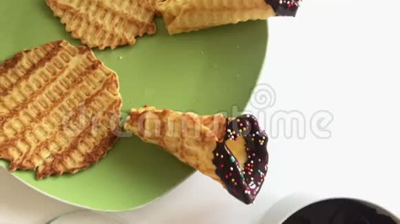 桌子上放着一个华夫饼锥蘸着融化的巧克力用多种颜色的花洒装饰视频的预览图