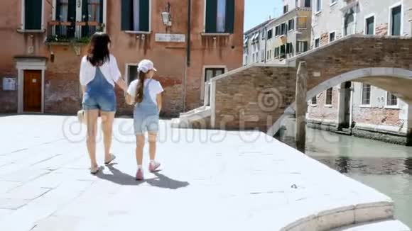 意大利威尼斯2018年7月7日一名年轻妇女和一名穿着相同牛仔工作服短裤的小女孩走在街上视频的预览图
