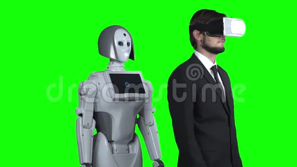 戴着虚拟现实眼镜的人把手放在一边机器人跟着他重复绿色屏幕慢慢视频的预览图
