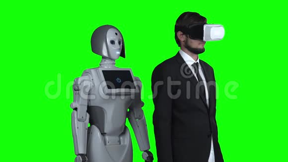 戴着虚拟现实眼镜的人和一个在机器人周围拉着的人在他后面重复绿色屏幕慢动作视频的预览图