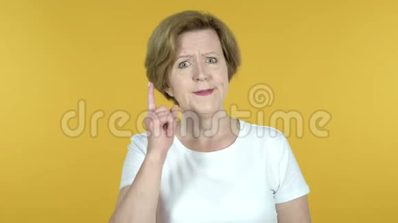 忧郁和愤怒的老妇人被隔离在黄色的背景上视频的预览图