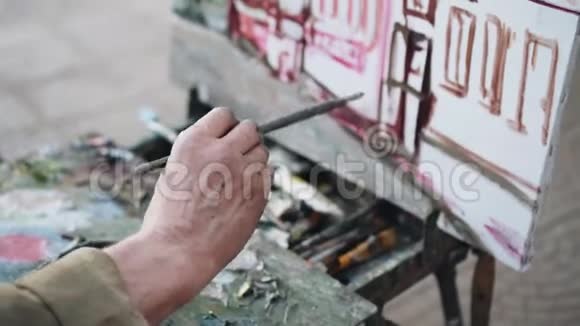 艺术家在街上画一幅画用刷子特写他的手美术视频的预览图