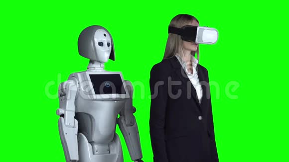戴着虚拟现实眼镜的女人举起手挥动机器人在她身后重复绿色屏幕慢慢视频的预览图