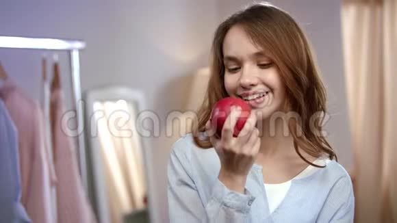 欢快的女人在家吃红苹果的肖像健康的女人吃水果视频的预览图