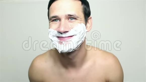 年轻的帅哥用剃须泡沫和微笑视频的预览图