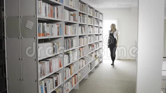 漂亮的金发女孩从大学图书馆的书架上拿书视频的预览图
