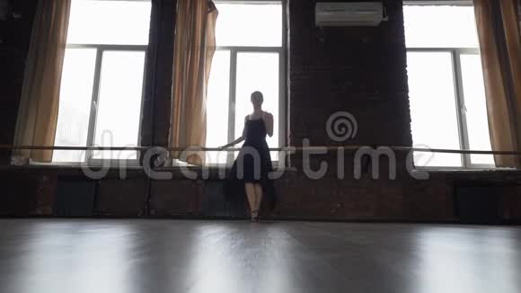 穿着黑色衣服的女孩在靠近窗户的地方缓慢地做着有趣的舞蹈动作视频的预览图