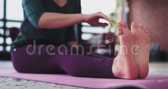 女士在家里练习瑜伽她早上在瑜伽垫上伸展腿和身体视频的预览图