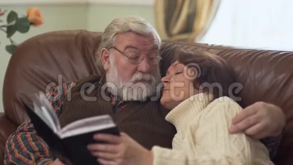 一对老夫妇坐在舒适的沙发上愉快地交谈怀旧和讨论一些事情视频的预览图