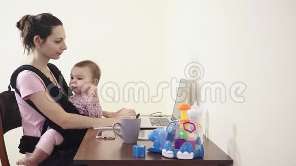 忙碌的母亲带着婴儿在家中的婴儿在办公室工作用手提电脑讲电话多任务视频的预览图