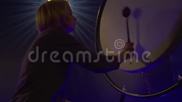 女人正在一个黑暗的房间里玩一个大的真实的鼓和一个特殊的打手视频的预览图