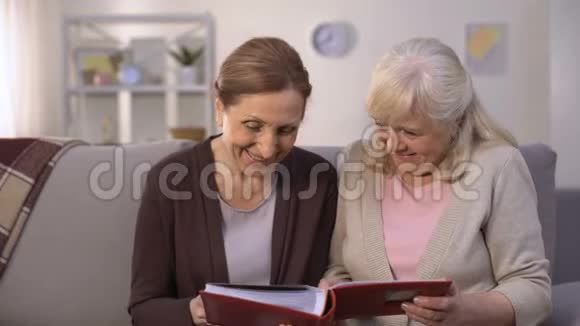 老年妇女在家庭相册中翻阅旧照片回忆快乐视频的预览图