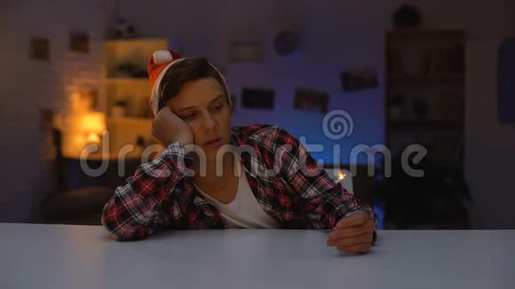 孤独的沮丧少年戴着圣诞帽庆祝新年手持孟加拉灯视频的预览图