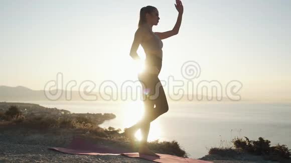 女性练习瑜伽和日出时做伸展运动的剪影视频的预览图