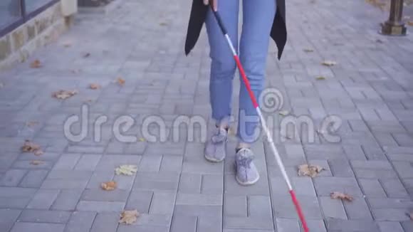 带着背包和眼镜的盲人女人拿着拐杖走在街上打着电话视频的预览图