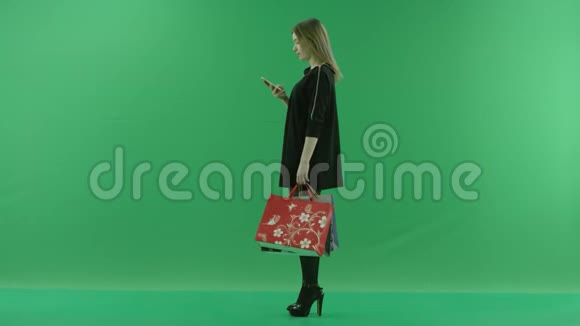 漂亮的年轻女性在等待某人时购物后在智能手机上输入短信chroma键绿色视频的预览图