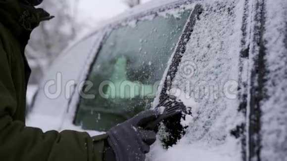 出行前用刮冰机清洗雪边车窗人从车窗上卸下冰男性视频的预览图