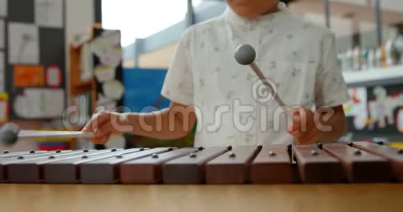 亚洲小学生在学校4k教室玩木琴的正面景色视频的预览图