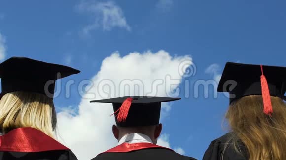 快乐的年轻人庆祝毕业把学术帽子抛在空中视频的预览图