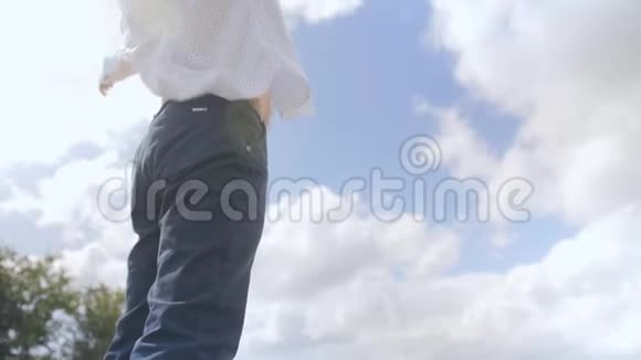 一个站立的人的侧视在云层和天空的背景下展开他的手臂中弹视频的预览图