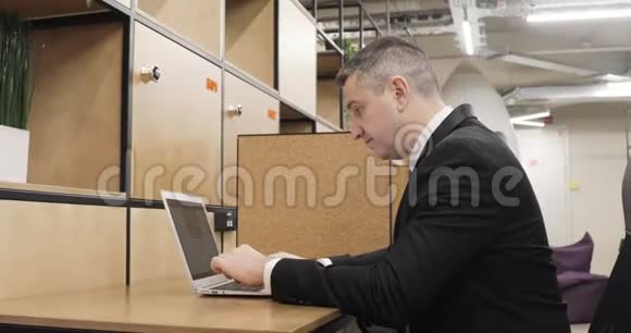 男士办公室经理正在现代同事中心工作笔记本电脑视频的预览图