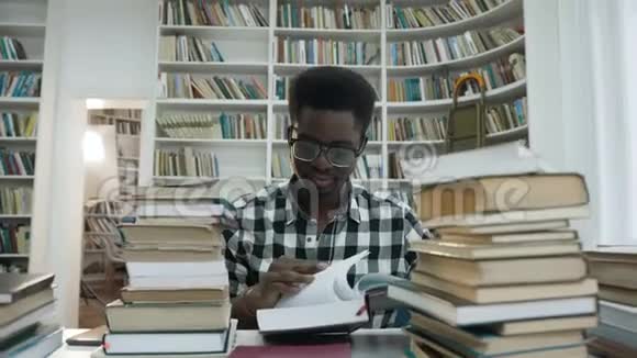 非洲年轻人坐在图书馆时戴眼镜看书的肖像视频的预览图