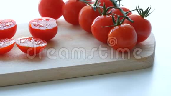 美丽多汁成熟的切好的红樱桃西红柿成簇白色桌子背景和木制厨房板视频的预览图