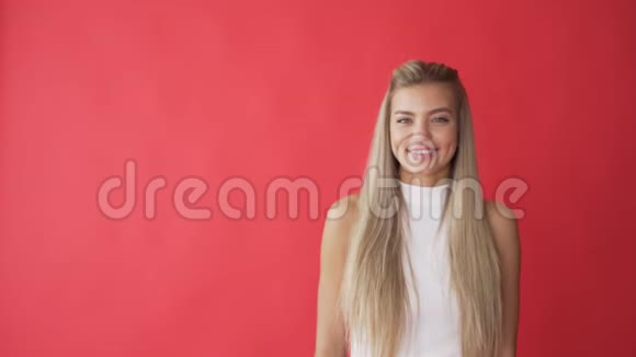微笑的年轻女子发送空气亲吻相机隔离在红色背景视频的预览图