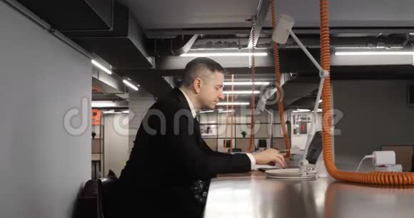 成熟的男性办公室经理坐在现代同事中心的笔记本电脑上工作视频的预览图