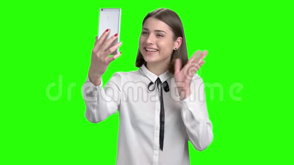 穿着白色衬衫的少女通过智能手机的网络摄像头交谈视频的预览图