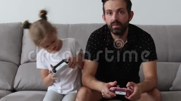 年轻的父亲和女儿玩电子游戏庆祝胜利嗨五岁视频的预览图