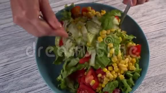 一个女人用西红柿草药和玉米搅拌两个叉子一份蔬菜沙拉视频的预览图
