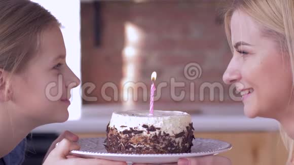 生日快乐妈妈小妈妈带着小女孩在节日蛋糕上吹蜡烛微笑着互相看着视频的预览图
