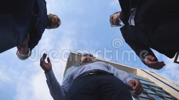 成功的商人站在办公楼附近把手叠在一起男同事伸出双臂视频的预览图