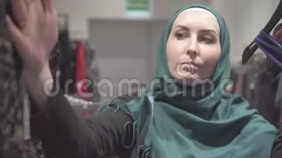 戴头巾的穆斯林妇女在店里挑选衣服特写视频的预览图