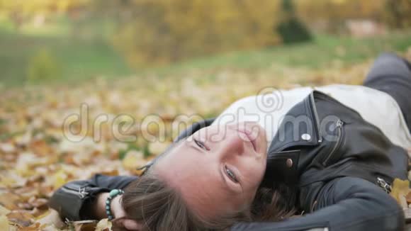 一个快乐的年轻女子躺在落叶中视频的预览图