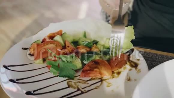 餐馆里的女孩吃一份漂亮的蔬菜沙拉盘子的边缘用酱汁装饰得很漂亮餐视频的预览图
