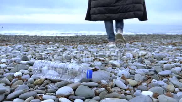 特写镜头一个女人在海滩上扔了一个空的塑料瓶视频的预览图