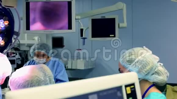 专业外科医生和助理在手术中交谈和使用计算机他们在现代医院工作视频的预览图