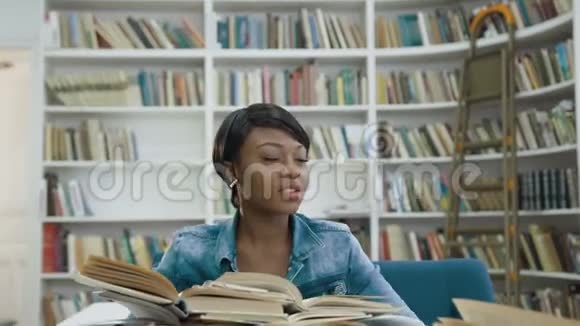 在图书馆学习了很长时间后疲惫的非洲女学生躺在书上视频的预览图