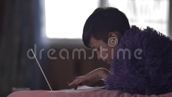 一个在家里用笔记本电脑拿着一杯热咖啡的男孩视频的预览图