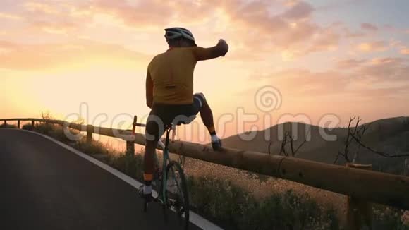 一位戴着头盔和运动器材的职业自行车手站在山的边缘可以看到美丽的景色视频的预览图