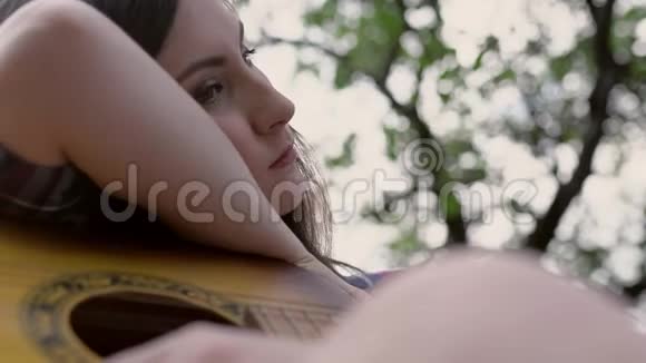 女孩在吉他上休息的特写视频的预览图