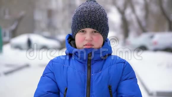 穿着蓝色羽绒服的少年扔雪冬天降雪特写视频的预览图