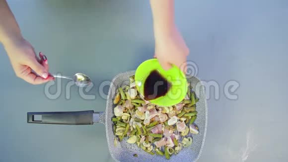 一个女人用绿豆和蘑菇把酱油加入鸡肉中视频的预览图