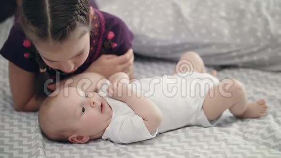 女孩亲吻躺在背上的新生婴儿神秘爱情概念视频的预览图