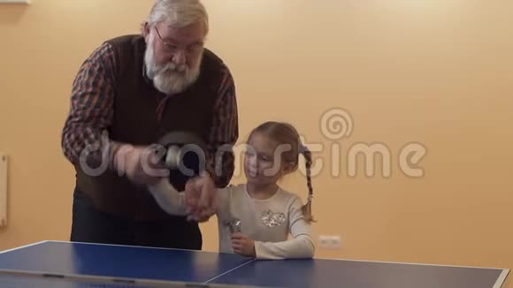 祖父教孙女打乒乓球小女孩把球打掉了享受幸福的家庭视频的预览图